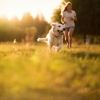 Photo of a dog running with owner at park.  