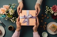 Hands exchanging gift box birthday flower table. 