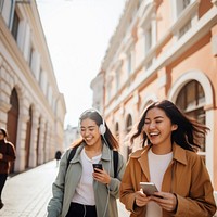 Two female asian friends laughing walking city. 