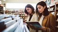 Two hispanic women publication bookstore shopping. 