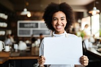 Mixed race female barista holding a white sign smiling adult cafe. 