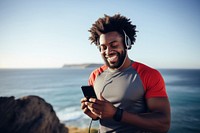 Photo of Portrait of a smiling afro-american sports man stretching his muscular arms before workout by the sea.  