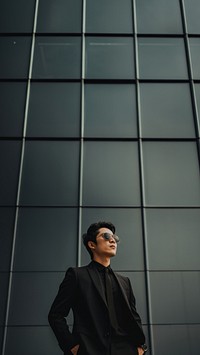 Photo of asian men look up the same way, wear suit and sunglasses.  