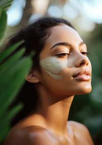 close up side profile photo of a hispanic woman face with subtle pastel green face mask cream.  