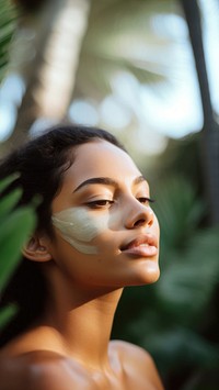 close up side profile photo of a hispanic woman face with subtle pastel green face mask cream.  