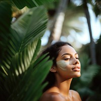 close up side profile photo of a hispanic woman face with subtle pastel green face mask cream.  