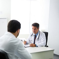 Photo of doctor is talking with patient and making notes while sitting in hospital.  