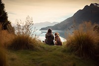 Back view photo of a hiker women sitting in a grass field with her dog looking at the lake. AI generated Image by rawpixel. 