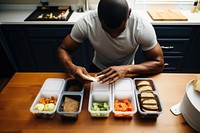 Man enjoying a homemade meal container table adult. AI generated Image by rawpixel.