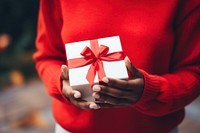 Red gift box sweater holding adult. 