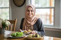 Muslim woman smiling eating plate. 