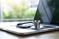 A medical stethoscope near a laptop on table computer electronics technology.