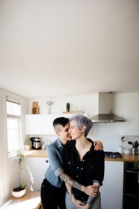 Smiling lesbian couple portrait kitchen kissing. 