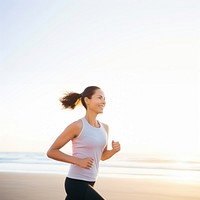 a portrait photo of a happy athletic woman jogging at sunrise by the beach.  