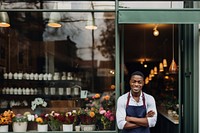 Photo of a cheerful small business owner standing and smiling in front of their shop.  