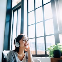 Photo of Asian woman smiling at home in headphones.  