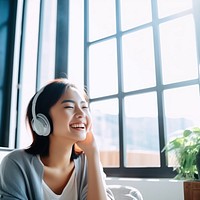 Photo of Asian woman smiling at home in headphones.  