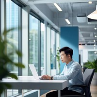 side view photo of an Asian office worker wearing casual clothes sitting in an office.  