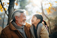 photo of Smiling happy older asian father with stylish short beard touching daughter's hand on shoulder looking and talking together.  