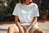 Woman wearing t-shirt sitting shorts outdoors. AI generated Image by rawpixel.