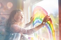 Girl painting rainbow on window  with bokeh effect