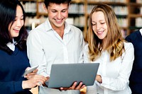 Diverse students using laptop in library