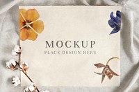 Cotton flower branch on a paper mockup over a creased gray fabric background