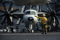 U.S. Navy Boatswain's Mate (Handling) 3rd Class Adrian Ramilo directs the pilots of an E-2C Hawkeye aircraft assigned to Airborne Early Warning Squadron (VAW) 115 on the flight deck of the aircraft carrier USS George Washington (CVN 73) in the South China Sea, Oct. 19, 2013.