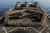 Marines with Combat Logistics Battalion 26, Fox Company and Echo Battery, Battalion Landing Team 2/6, 26th Marine Expeditionary Unit (26th MEU) and Sailors assigned to the amphibious transport dock ship USS Arlington (LPD 24) pose for a photo on the flight deck of the Arlington Jan. 10, 2016.
