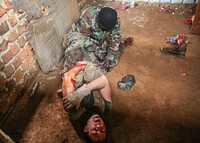 Petty Officer 2nd Class Robert Otte, corpsman and chief instructor with Special-Purpose Marine Air-Ground Task Force Crisis Response-Africa, acts as a casualty as a Uganda People’s Defense Force medic applies a tourniquet during a notional tactical combat casualty care exercise at Camp Singo, Uganda, Dec. 10, 2015.