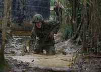 160112-N-YG415-010 OKINAWA, Japan (Jan. 12, 2016) Construction Electrician Constructionman Jacob H. Raines, assigned to Naval Mobile Construction Battalion (NMCB) 3, fights through knee-high mud and water while running a six-hour endurance course at the Marine Corps Jungle Warfare Training Center (JWTC).