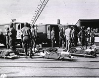 Soldiers on stretchers await ambulances to take them to the wards (1944). African Americans, serving on the litter squad, are standing among wounded soldiers on stretchers. Original public domain image from Flickr