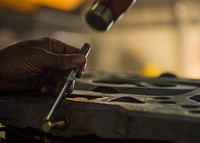 Tech. Sgt. Matthew Heeter, 455th Expeditionary Aircraft Maintenance Squadron aerospace ground equipment floor lead, uses a hammer to tap a punch while replacing a tilt cycle on a munitions lift, Bagram Airfield, Afghanistan, Sept. 22, 2016.