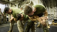 U.S. Marine Corps Sgt. Colton Ciufo, left, and Sgt. Matt Hennies, right, psychological operations specialists, simulate the detention of Cpl. Patrick Esponla, center, a chemical, biological, radiation, nuclear defense specialist with the Command Element, 13th Marine Expeditionary Unit (MEU), after being sprayed by Oleoresin Capsicum Spray, aboard the Wasp-class amphibious assault ship USS Essex (LHD 2), Nov. 23, 2018, in the Arabian Gulf. The Essex is the flagship for the Essex Amphibious Ready Group and, with the embarked 13th MEU, is deployed to the U.S. 5th Fleet area of operations in support of naval operations to ensure maritime stability and security in the Central Region, connecting the Mediterranean and the Pacific through the western Indian Ocean and three strategic choke points.