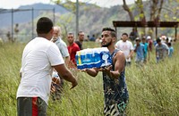 Local residents form a chain to offload food and water from a U.S. Customs and Border Protection, Air and Marine Operations, UH-60 Black Hawk helicopter as its crew delivers humanitarian aid to their community in Puerto Rico, October 12, 2017.