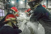 U.S. Sailors assigned to the amphibious dock landing ship USS Ashland (LSD 48) hold applied banding patches as water is charged through a cracked pipe during the Damage Control Wet Trainer Course in Yokosuka, Japan, Oct. 19, 2017.