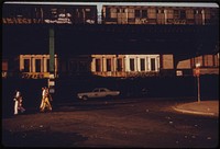 Inner City Residents of Brooklyn in New York City Walk Along Bushwick Avenue Oblivious to the Noise of the Graffiti Garbed Elevated Train.