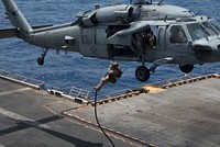 A U.S. Marine assigned to the 26th Marine Expeditionary Unit, fast ropes from an MH-60S Sea Hawk helicopter attached to Helicopter Sea Combat Squadron (HSC) 28, to the flight deck of the Wasp-class amphibious assault ship USS Iwo Jima (LHD 7), during a fast rope exercise in the 5th Fleet Area of Operations, May 21, 2018.