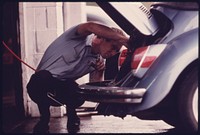 Service Station Mechanic Adjusts the Engine for a Young Woman Whose Vehicle Had Failed the Emissions Test at an Auto Emission Inspection Station in Downtown Cincinnati, Ohio. Although the Station Does Not Have the Same Type of Exhaust Analyzer That the City Uses, He Will Be Able to Adjust the Carburetor to Pass Inspection.