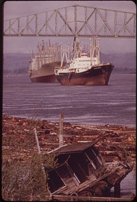 Freighters Coming Into Dock at Rainier, Oregon, on the Columbia River. Old Lumberman's Shack, Uprooted by Wind and Weather, Seems Ready to Slide Into Log Boom 04/1973. Photographer: Falconer, David. Original public domain image from Flickr