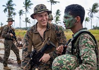 U.S. Marine Corps Pfc. Erik Anderson speaks with a Royal Malaysian marine after completing a simulated beach assault during Cooperation Afloat Readiness and Training (CARAT) 2018 at Tanduo Beach, Malaysia, Aug. 17, 2018.