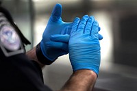 An officer with U.S. Customs and Border Protection Office of Field Operations gestures with gloved hands as he speaks with an arriving international traveler at Dulles International Airport in Dulles, Va., March 18, 2020.