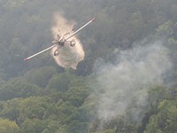 Dempsey FireFire Boss Single Engine Airtanker dumping water over a fire.