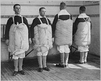 Recruits with their mattresses tied to them to serve as life preservers. Photo taken at Newport Naval Training Station, Rhode Island. Underwood and Underwood., 04/1917. Original public domain image from Flickr