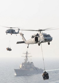 U.S. Navy MH-60S Knighthawk helicopters assigned to Helicopter Sea Combat Squadron (HSC) 23 transfer supplies from the fast combat support ship USNS Bridge (T-AOE 10) to the aircraft carrier USS Ronald Reagan (CVN 76) during a replenishment at sea in the Persian Gulf May 31, 2011.