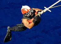 U.S. Navy Electronics Technician 3rd Class Jonathan A. Simmons, a search and rescue swimmer assigned to the amphibious transport dock ship USS Denver (LPD 9), is lowered from the forecastle during a man overboard drill in the East China Sea Sept. 27, 2011.