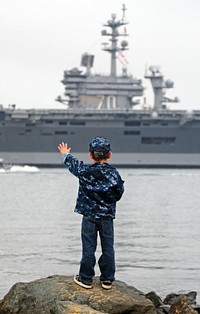 The son of U.S. Navy Electrician's Mate 1st Class Randall White waves to his father's ship, the aircraft carrier USS Carl Vinson (CVN 70), as it transits San Diego Bay Nov. 30, 2011, after departing Naval Air Station North Island on a scheduled deployment to the western Pacific region.