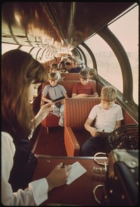 An Amtrak passenger service representative calls bingo numbers to interested passengers while others sleep in the lounge car of the Empire Builder enroute from Chicago to East Glacier Park, Montana, and Seattle, Washington.