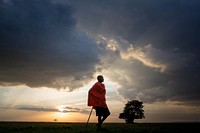Josphat Mako, Maasai guide and companion to author and travel writer Stuart Butler stands as the sun begins to set over the Mara North Conservancy adjacent to Kenya's world famous Maasai Mara National Reserve