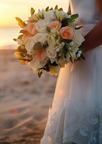 Closeup groom and bride have bouquet at the sunset beach, focus on bouquet.  